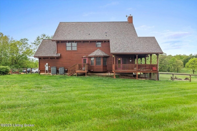 rear view of property with cooling unit, a lawn, a chimney, and roof with shingles