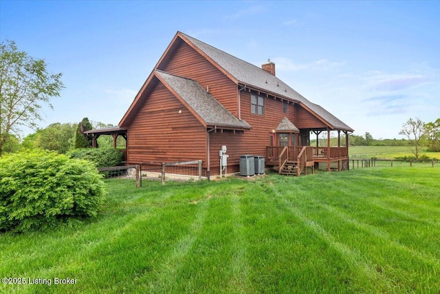 back of house with a deck, a chimney, cooling unit, and a shingled roof