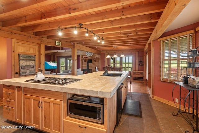 kitchen featuring appliances with stainless steel finishes, a sink, tile countertops, baseboards, and wooden ceiling