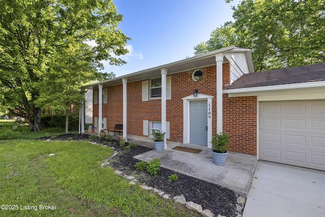 bi-level home with a garage, brick siding, and a front lawn