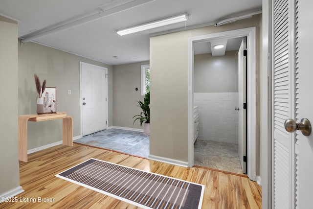 hall featuring wood finished floors and tile walls