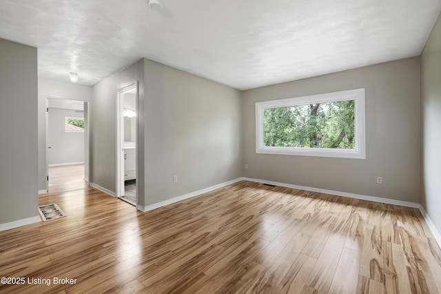 unfurnished room featuring light wood-type flooring, baseboards, and a smoke detector