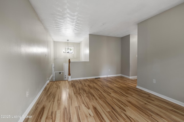 unfurnished dining area with light wood finished floors, baseboards, and a chandelier