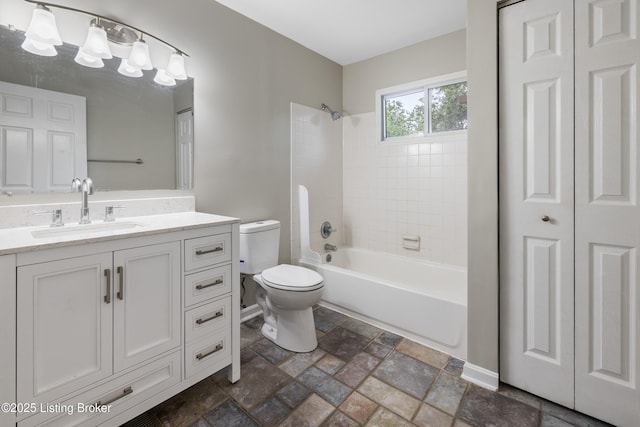 full bathroom with vanity, toilet, bathing tub / shower combination, stone tile floors, and baseboards