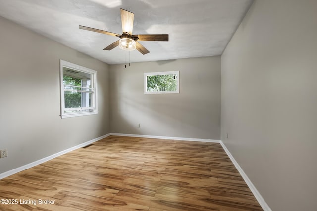 spare room featuring light wood finished floors, ceiling fan, and baseboards
