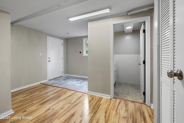 corridor with wood finished floors and tile walls