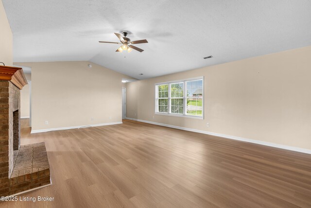 unfurnished living room featuring a ceiling fan, wood finished floors, a fireplace, baseboards, and lofted ceiling