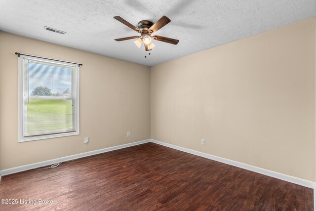 spare room with dark wood-type flooring, a ceiling fan, baseboards, and a textured ceiling