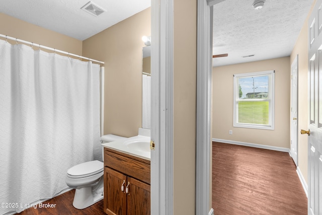 bathroom with wood finished floors, toilet, a textured ceiling, and vanity