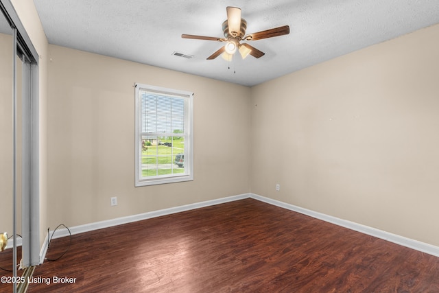 spare room with wood finished floors, a ceiling fan, baseboards, and a textured ceiling