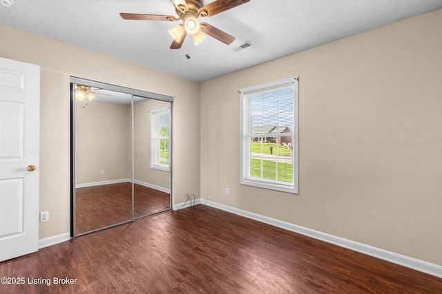 unfurnished bedroom featuring wood finished floors, multiple windows, a closet, and baseboards