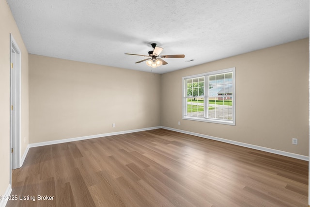 unfurnished room featuring wood finished floors, ceiling fan, baseboards, and a textured ceiling