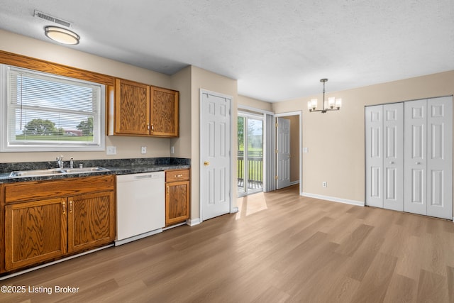 kitchen with dishwasher, a sink, light wood-style floors, a chandelier, and a textured ceiling