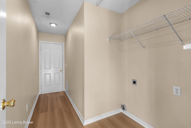 laundry room with hookup for an electric dryer, wood finished floors, and baseboards