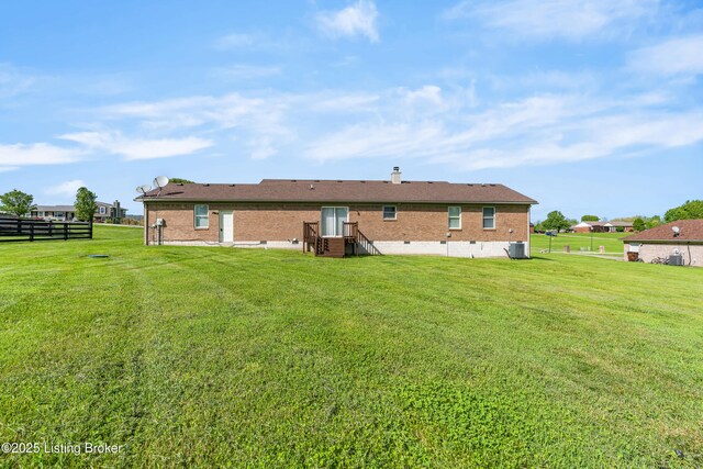 back of house with brick siding, a chimney, and central air condition unit