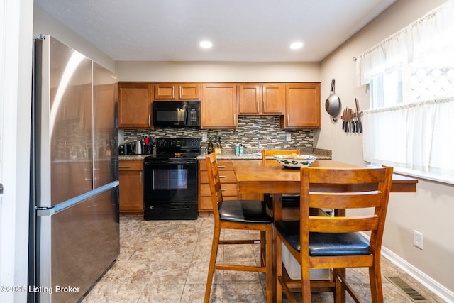 kitchen with black appliances, backsplash, brown cabinets, and a sink