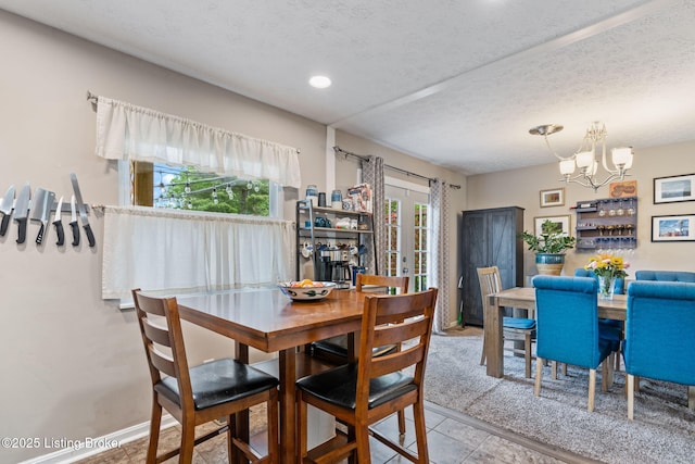 tiled dining area with a chandelier and a textured ceiling
