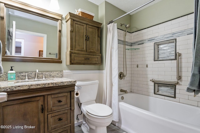 full bath with toilet, a wainscoted wall, shower / bathtub combination with curtain, and vanity