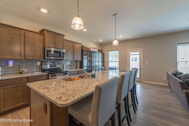 11905 Parkside Vista Ln, Louisville, KY 40229 - kitchen featuring appliances with stainless steel finishes, a sink, dark wood finished floors, decorative backsplash, and light stone countertops
