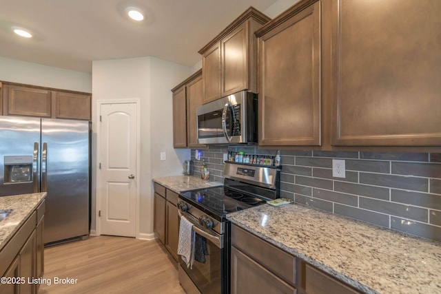 11905 Parkside Vista Ln, Louisville, KY 40229 - kitchen featuring appliances with stainless steel finishes, light wood-style flooring, backsplash, light stone counters, and recessed lighting