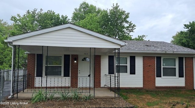 view of front of house featuring brick siding, fence, a porch, and a shingled roof
