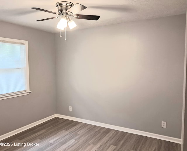 spare room featuring dark wood-style floors, baseboards, and ceiling fan