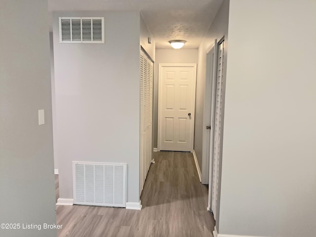 hallway featuring wood finished floors and baseboards