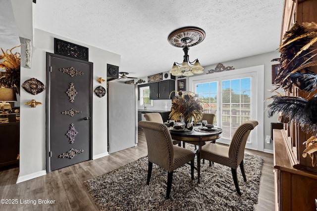1507 Hobart Ct, Louisville, KY 40216 - dining room with a chandelier, wood finished floors, a textured ceiling, and baseboards