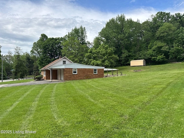 rear view of property featuring a lawn, a shed, driveway, an outdoor structure, and brick siding