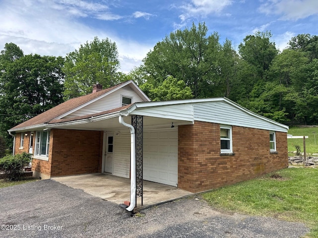 view of front of property featuring brick siding, asphalt driveway, a carport, a chimney, and a front yard