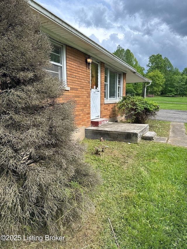 property entrance with a yard and brick siding