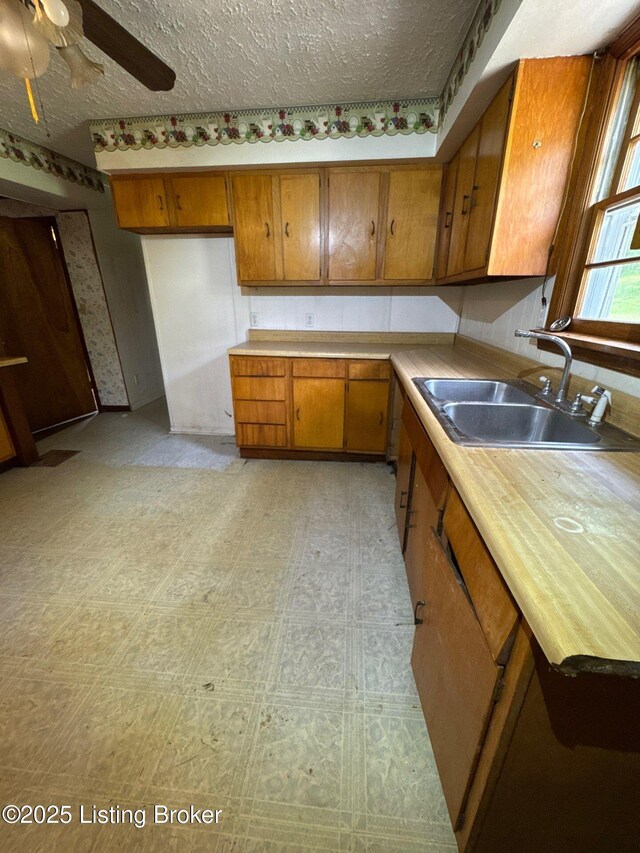 kitchen featuring a sink, brown cabinetry, a ceiling fan, light countertops, and light floors