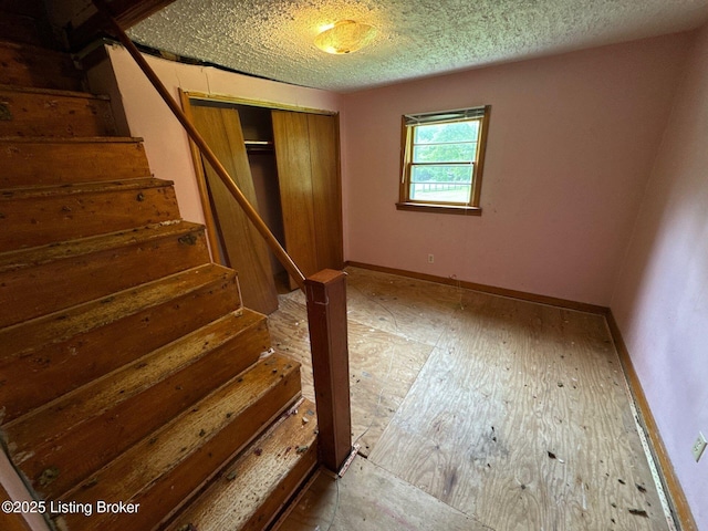 below grade area featuring baseboards, stairs, and a textured ceiling