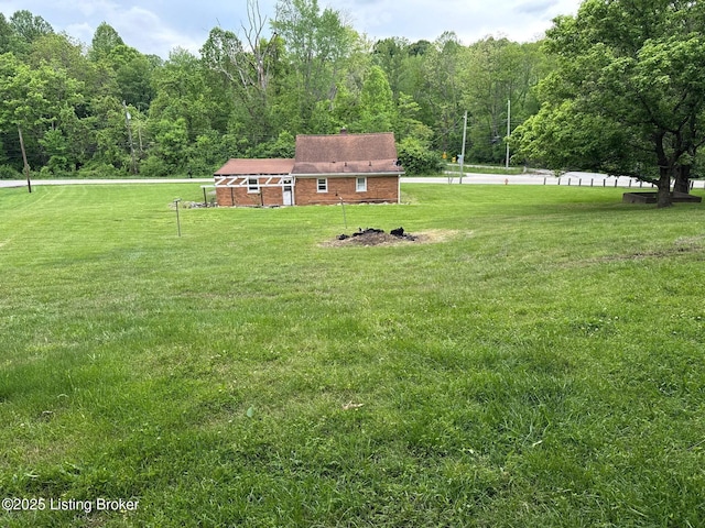view of grassy yard with a view of trees