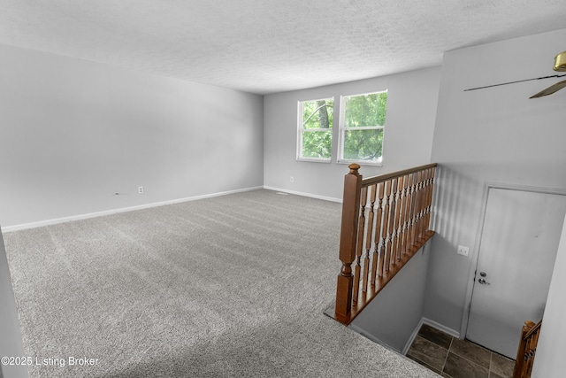 carpeted empty room featuring a textured ceiling, baseboards, and ceiling fan