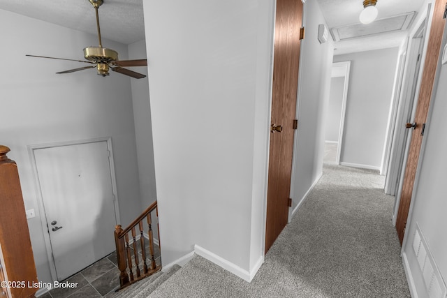 corridor with an upstairs landing, carpet flooring, baseboards, and attic access