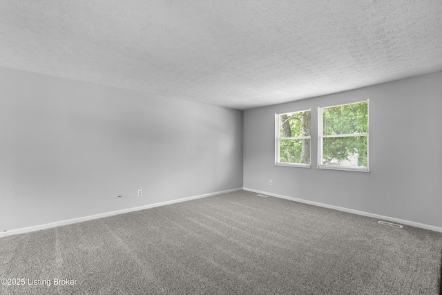 carpeted spare room featuring a textured ceiling and baseboards