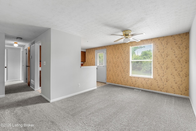 unfurnished room featuring ceiling fan, carpet floors, baseboards, and a textured ceiling