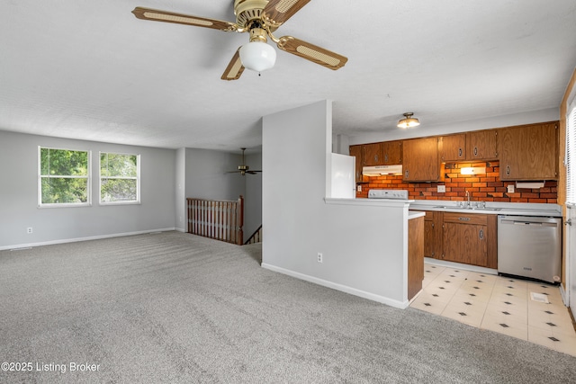 kitchen featuring dishwasher, under cabinet range hood, brown cabinets, ceiling fan, and freestanding refrigerator