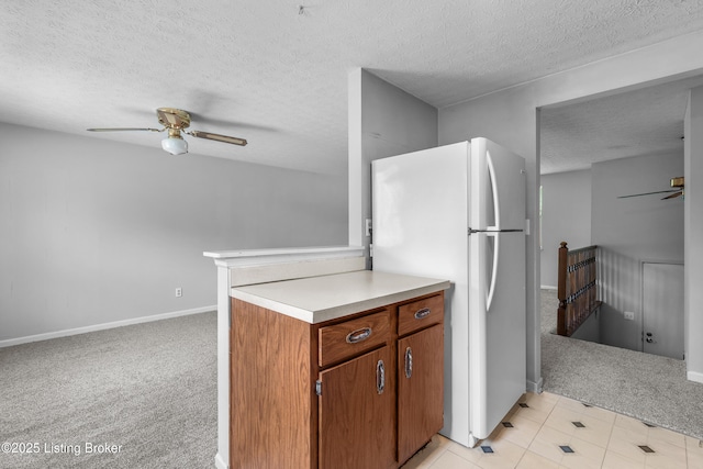 kitchen featuring freestanding refrigerator, a ceiling fan, light colored carpet, a textured ceiling, and baseboards