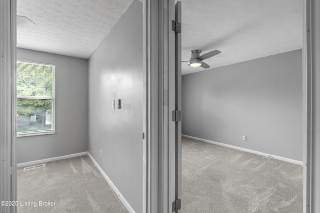 corridor with a textured ceiling, carpet floors, and baseboards