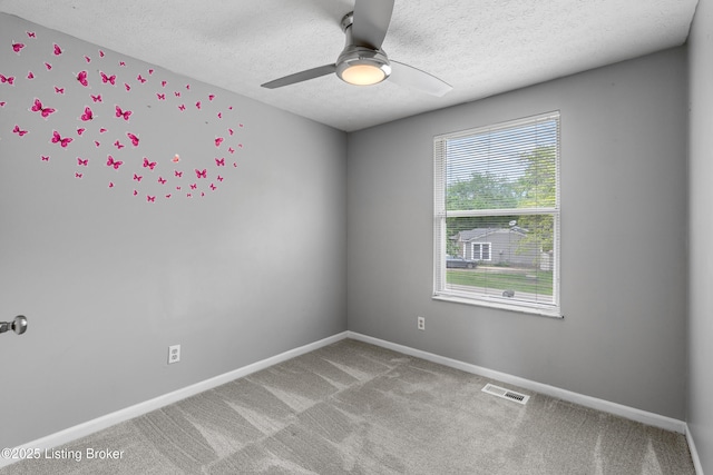 empty room featuring a textured ceiling, light carpet, a ceiling fan, and baseboards