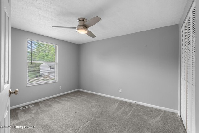 unfurnished room with carpet flooring, a ceiling fan, baseboards, and a textured ceiling