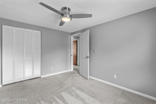 unfurnished bedroom featuring carpet, baseboards, a closet, and a ceiling fan