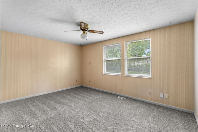 carpeted empty room featuring a ceiling fan, baseboards, and a textured ceiling