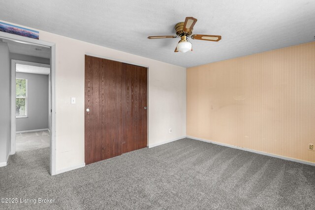 unfurnished bedroom featuring carpet, a closet, baseboards, and a ceiling fan