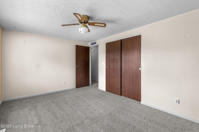 unfurnished bedroom featuring carpet floors, a closet, a textured ceiling, baseboards, and ceiling fan