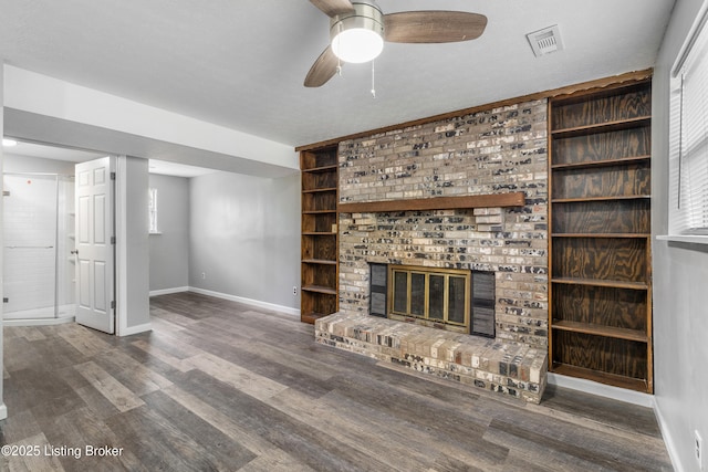 unfurnished living room featuring baseboards, wood finished floors, a fireplace, a ceiling fan, and built in features