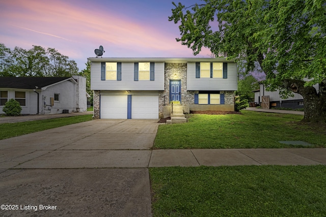 raised ranch with an attached garage, driveway, and a front yard