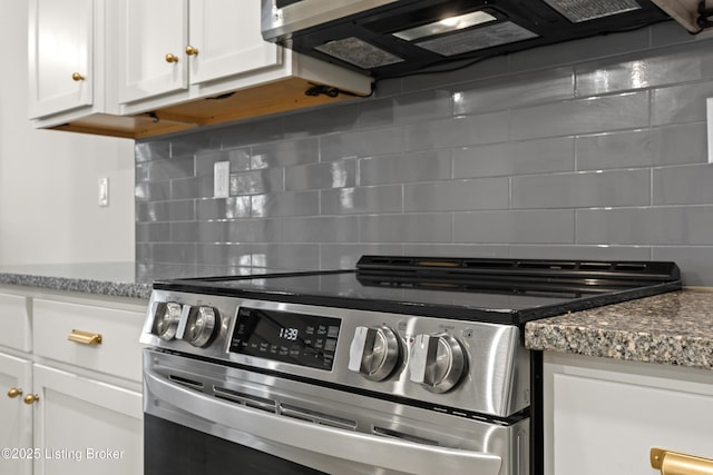 kitchen with stainless steel electric range oven, exhaust hood, tasteful backsplash, white cabinetry, and stone countertops